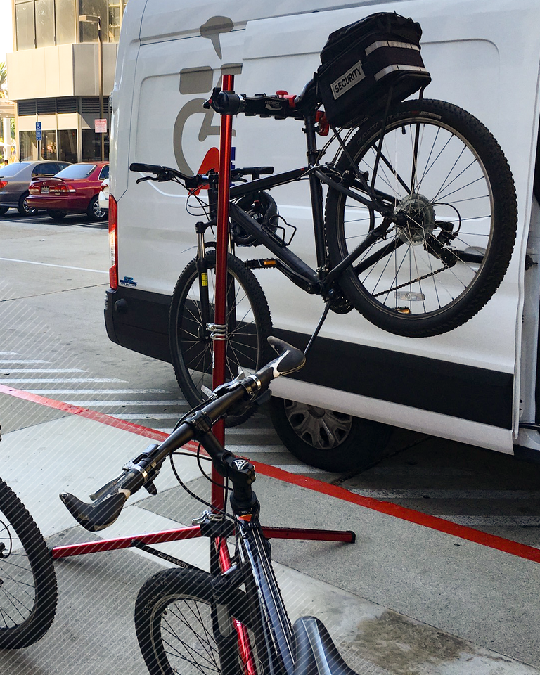 A Security Patrol Bike on a bike stand being worked on outside by the mobile bike shop van. 