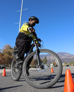 A security officer riding their patrol bike doing cone maneuvers during a bike patrol training class. 
